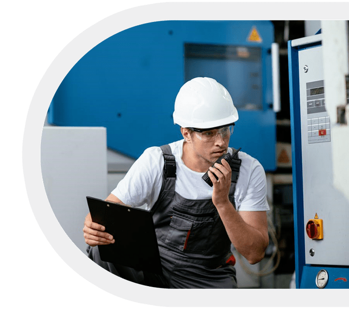 Factory worker using a Motorola two-way radio while inspecting equipment.