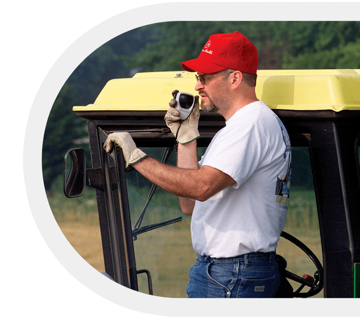 Farmer using a handheld two-way radio inside a tractor.