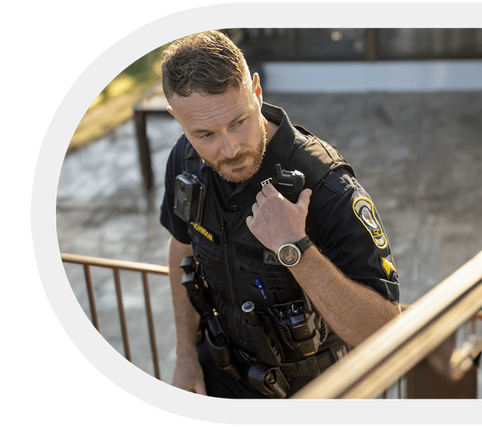 Security officer holding a Motorola two-way radio outdoors.