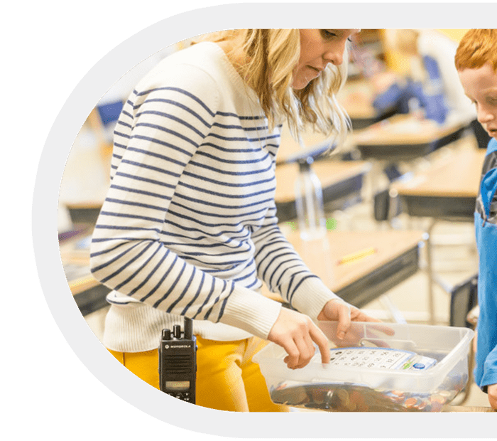 Teacher with a Motorola two-way radio in a classroom setting.