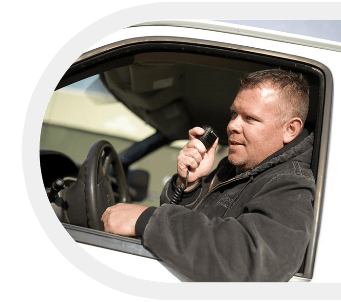 Man speaking into a vehicle-mounted two-way radio.